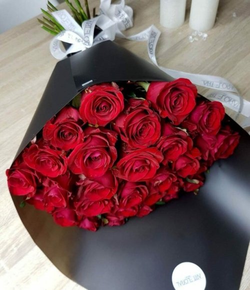Eleganter Blumenstrauß aus roten Rosen in moderner schwarzer Geschenkverpackung