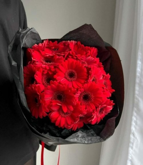 Blumenstrauß mit roten Gerbera in schwarzer Verpackung