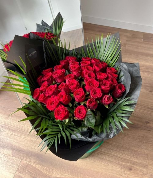 Blumenstrauß mit roten Rosen in schwarzer Verpackung