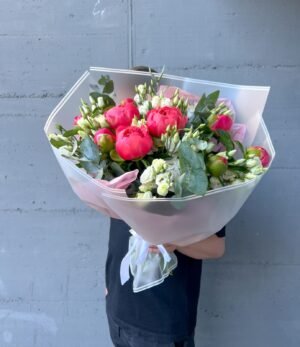 Handgebundener Blumenstrauß mit korallenfarbenen Pfingstrosen und zarten weißen Lisianthus-Blüten