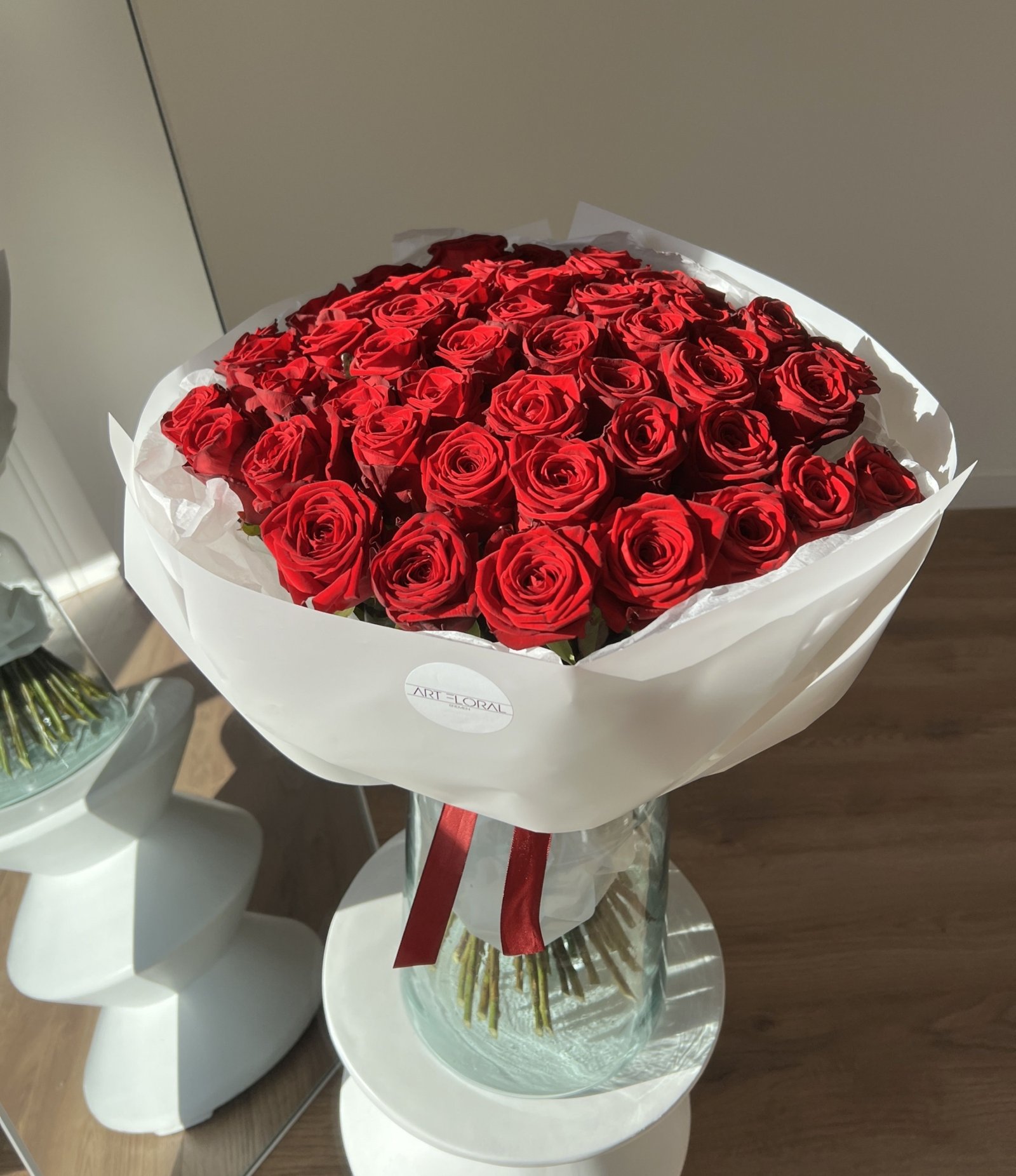 Blumenstrauß 50 Rosen mit tiefroten Rosen in weißer Verpackung.