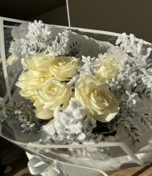 Winterlicher Strauß aus weißen Rosen und schneeweißen Ruscus-Zweigen mit kleinem Deko-Vogel.