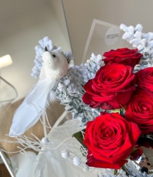 Rote Rosen im weihnachtlichen Arrangement „Winterrose“ kombiniert mit weißem, schneebedecktem Ruscus.