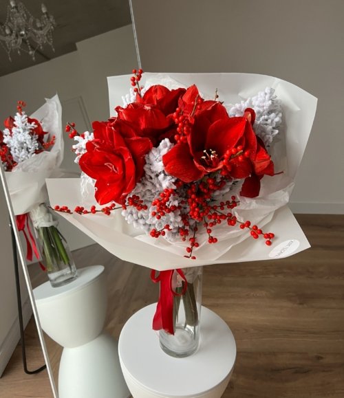 Blumenstrauß Roter Frost mit rotem Amaryllis, Ilex und verschneiten Zweigen in weißer Verpackung.
