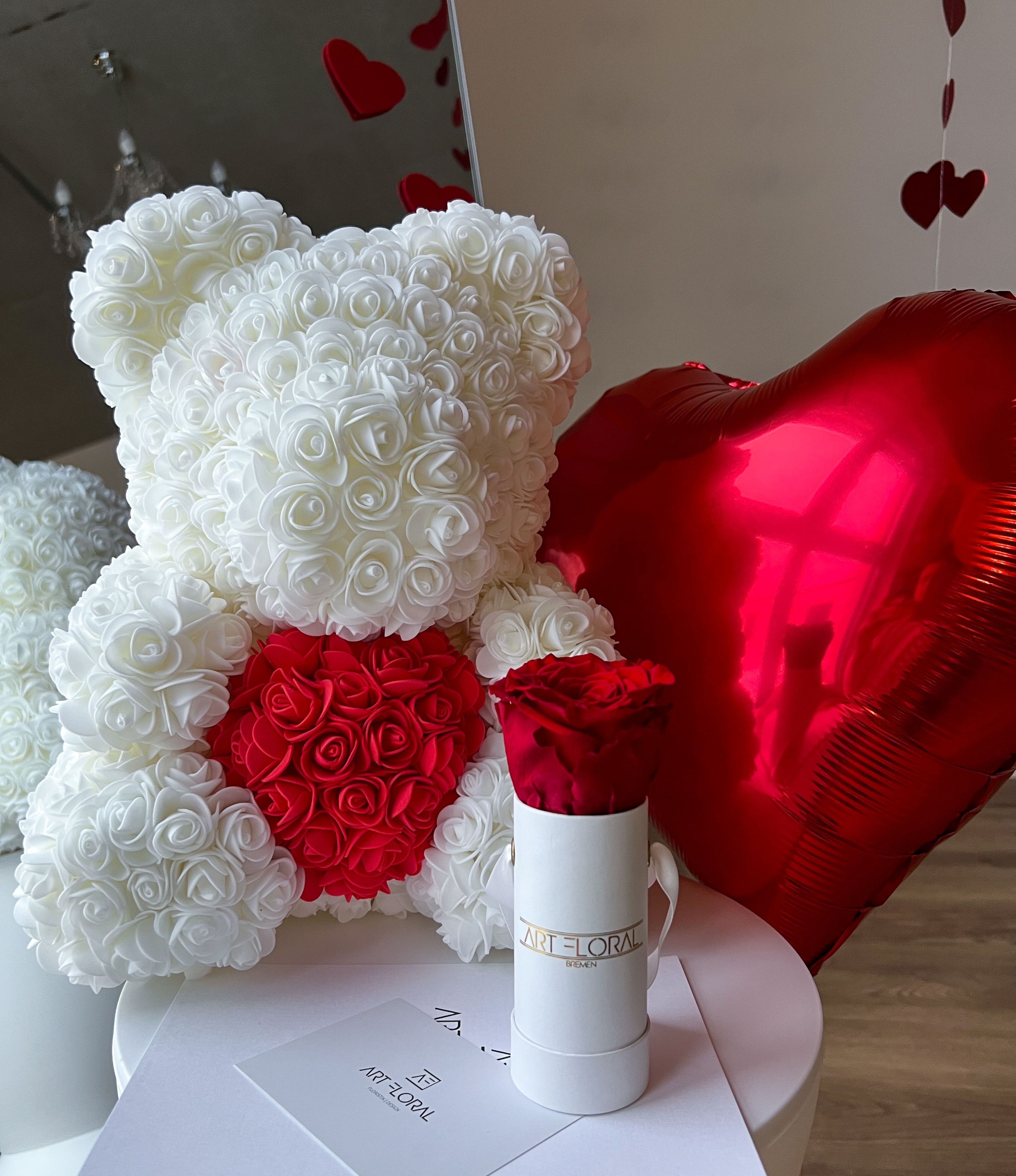 Weißer Rosenbär mit rotem Herz und rotem Herzballon