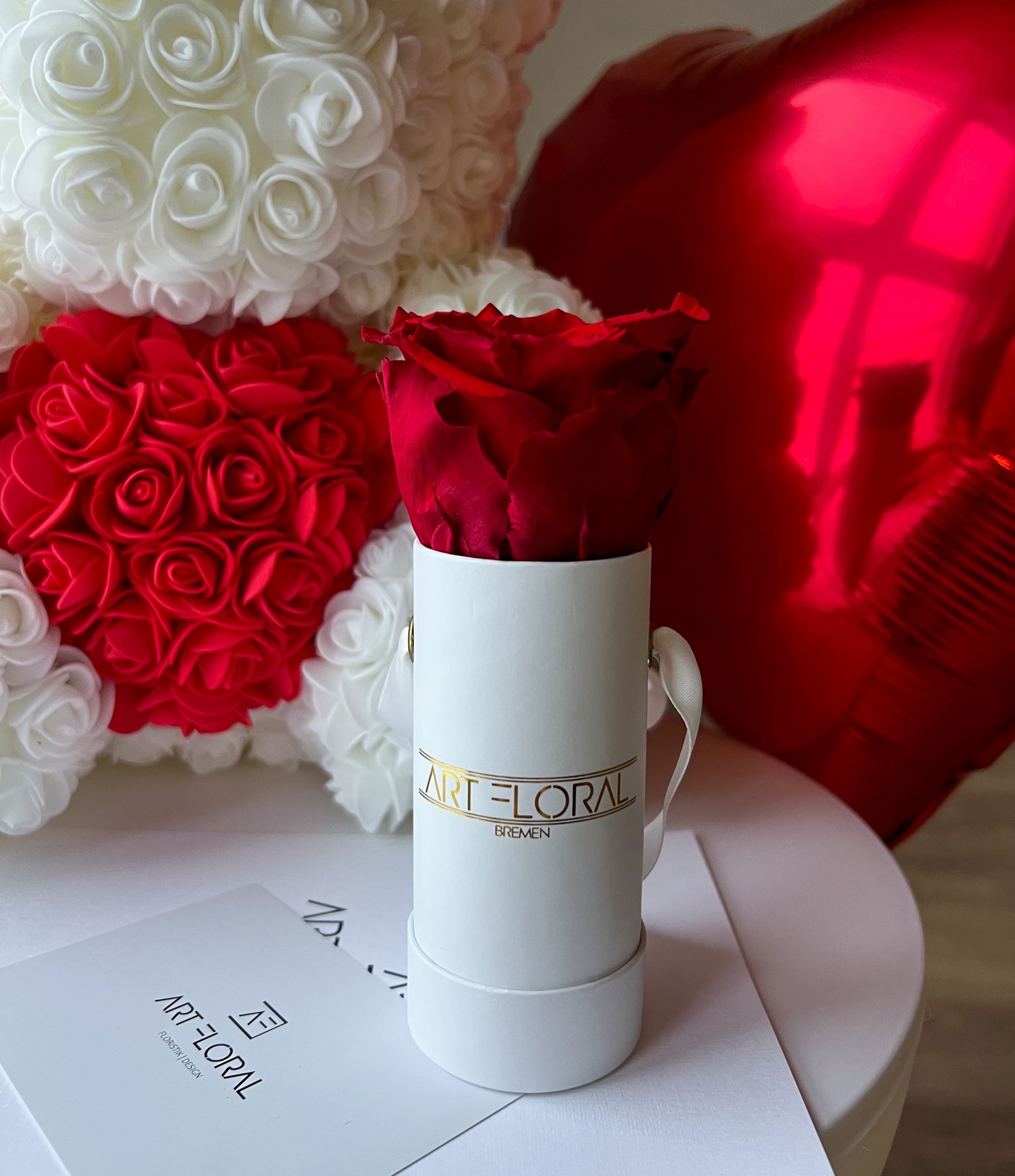 Weißer Rosenbär mit rotem Herz und rotem Herzballon